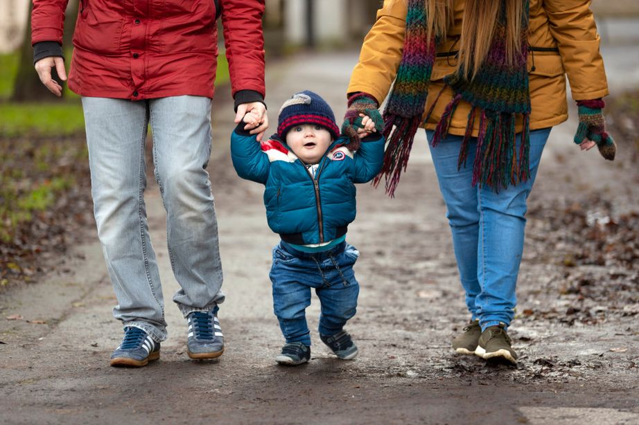 Parents walking and holding hands with toddler in the middle