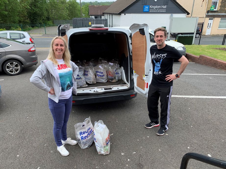 A woman and a man standing outside van with food parcels